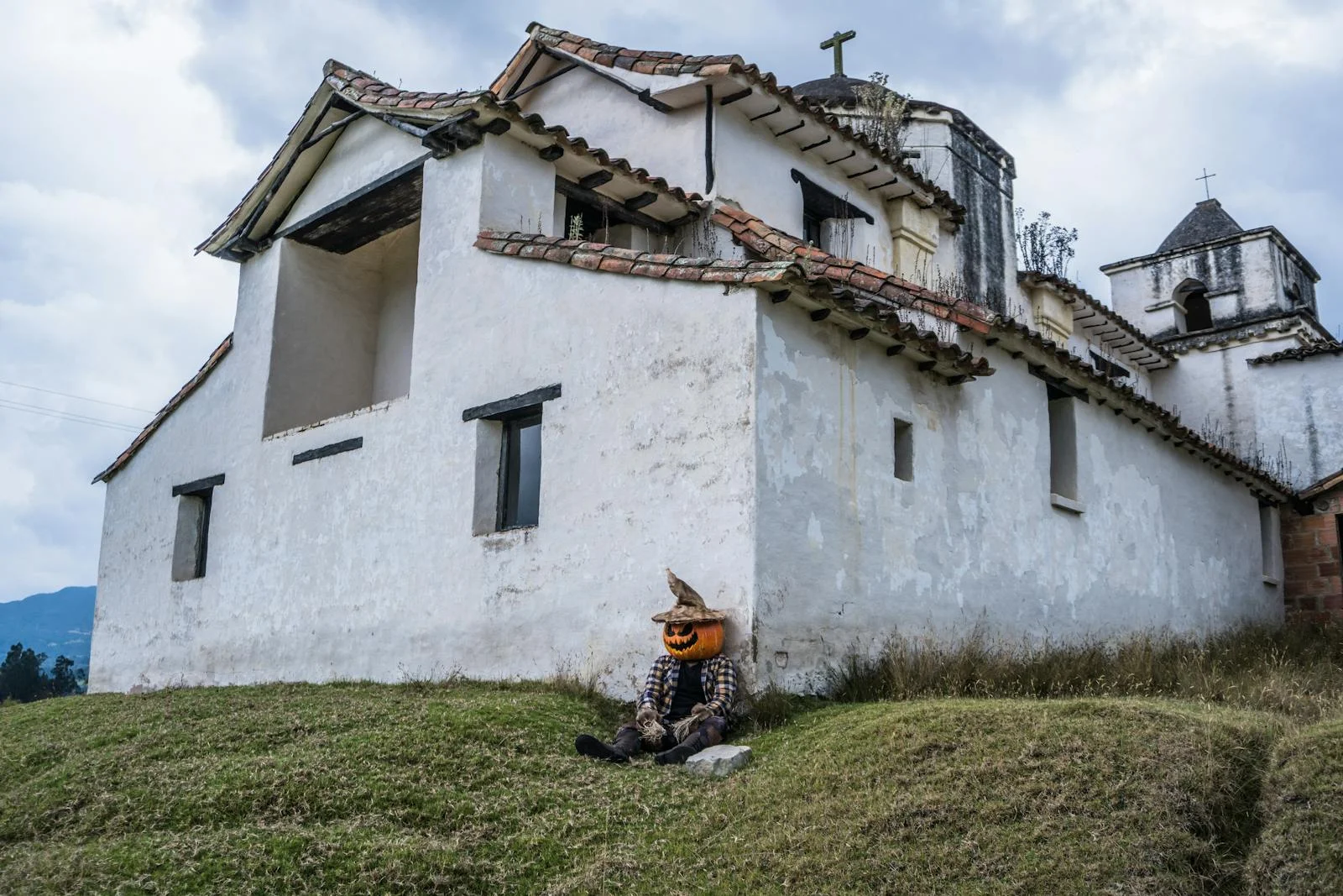 Unveiling Japan's Nagoro Scarecrow Village: Dolls in the Forest, a Hauntingly Beautiful Story - A Halloween scarecrow with a pumpkin head sits by a historic church in Guasca, Colombia.